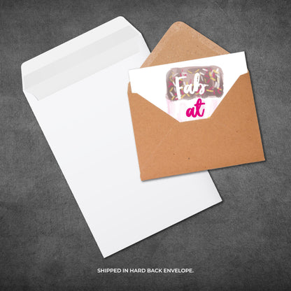Card with 'Fab at' design in a brown envelope on a gray background
