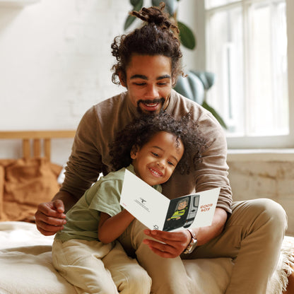 Man and child sitting together, looking at a book in a cozy room.