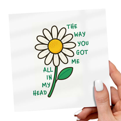 Card with a daisy illustration and text held by a hand