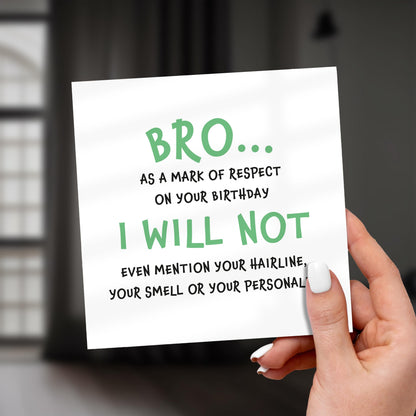 Hand holding a card with humorous birthday message on a blurred background