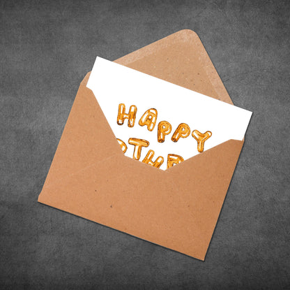 Brown envelope with a white card inside displaying 'HAPPY BIRTHDAY' in gold letters on a dark gray background.