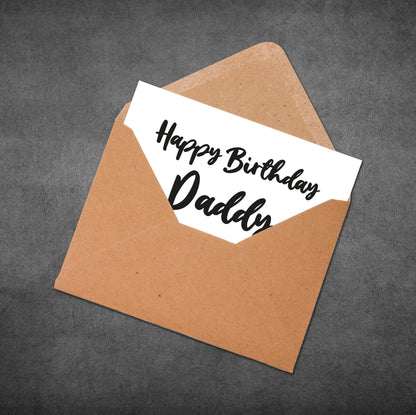 Brown envelope with a white card inside reading 'Happy Birthday Daddy' on a dark gray background