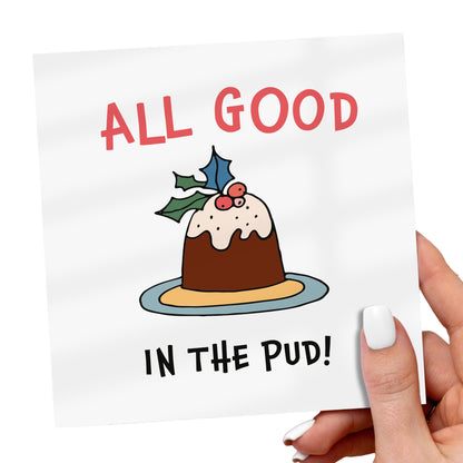 Card with a Christmas pudding illustration and text 'All good in the pud!' held by a hand.