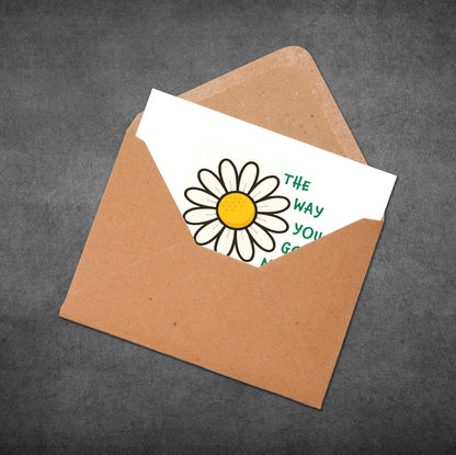 Brown envelope with a white card featuring a daisy illustration and text on a dark gray background