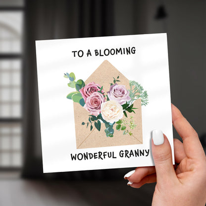 Card with floral design and text held by a hand, against a blurred background