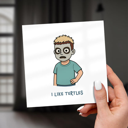 Card with a cartoon character holding a turtle and text 'I LIKE TURTLES' held by a hand.