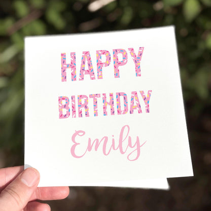 Hand holding a birthday card with 'Happy Birthday Emily' text.