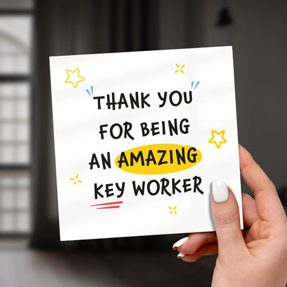 Hand holding a card that says 'Thank you for being an amazing key worker' with decorative elements.