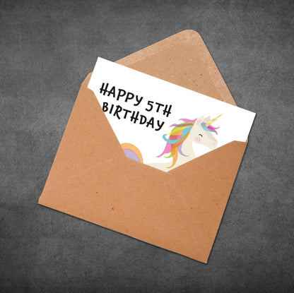 Happy 5th birthday card with a unicorn illustration in an open brown envelope on a dark gray background