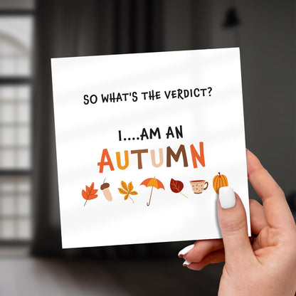 Hand holding a card with autumn-themed text and illustrations.