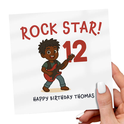 Birthday card with a cartoon character playing guitar, text 'Rock Star! 12' and 'Happy Birthday Thomas'.