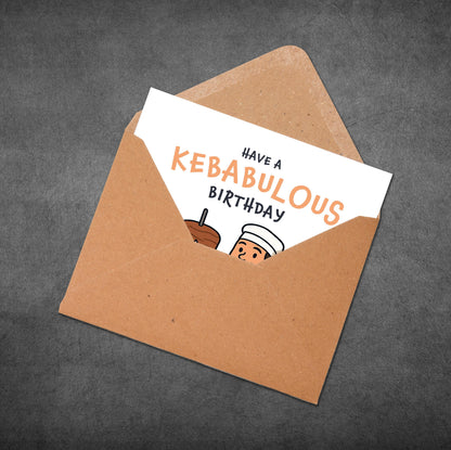 Greeting card with 'Have a Kebabulous Birthday' text and illustration in an open brown envelope on a dark gray background.