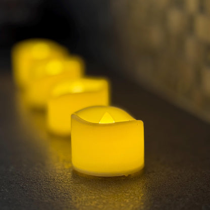Row of glowing yellow candles on a textured surface with a blurred background