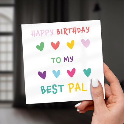 Hand holding a birthday card with colorful hearts and text.