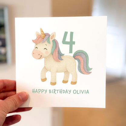 Hand holding a birthday card with a unicorn illustration and the number 4, personalized for Olivia.