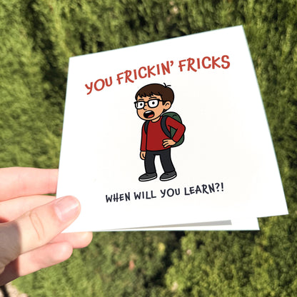 Card with a cartoon character and text held by a hand against a green background