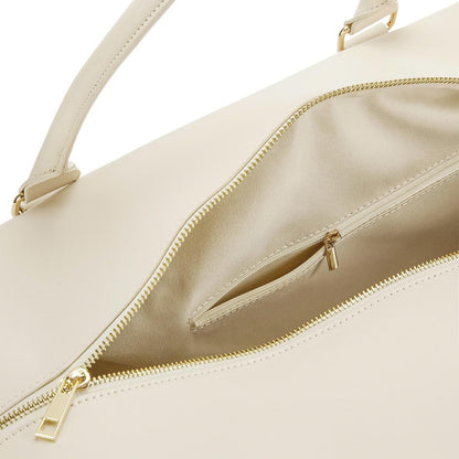 Close-up of a beige handbag with gold zippers and handles.