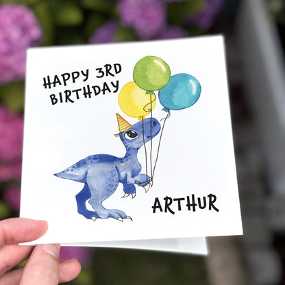 Birthday card with a dinosaur holding balloons and 'Happy 3rd Birthday Arthur' text.
