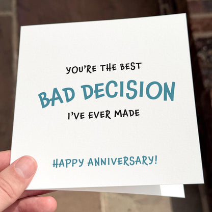 Card with humorous text 'You're the best bad decision I've ever made. Happy anniversary!' held by a hand.