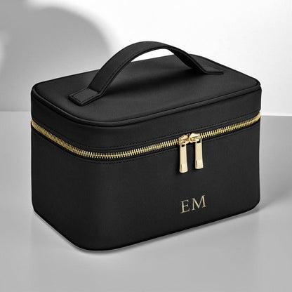 Black cosmetic bag with gold zipper and initials on a gray background