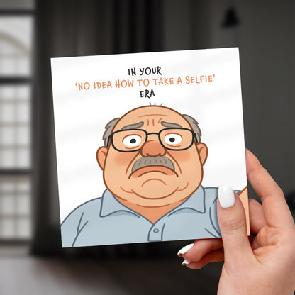 Cartoon character holding a card with text about taking selfies, held by a hand.