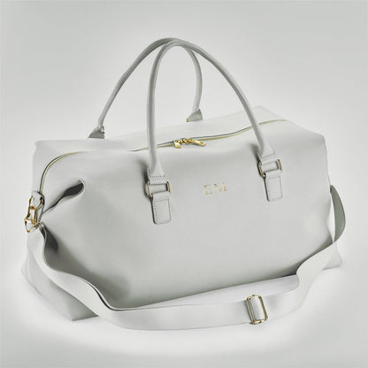 Light gray duffel bag with gold accents on a light gray background