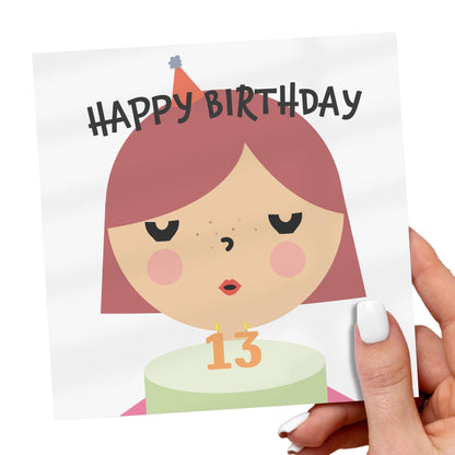 Birthday card with a cartoon girl's face and 'Happy Birthday' text, held by a hand.