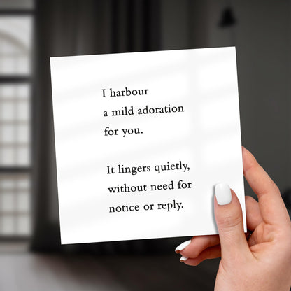 Hand holding a card with romantic text against a blurred background