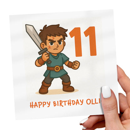 Birthday card with a character holding a sword and the number 11, held by a hand.