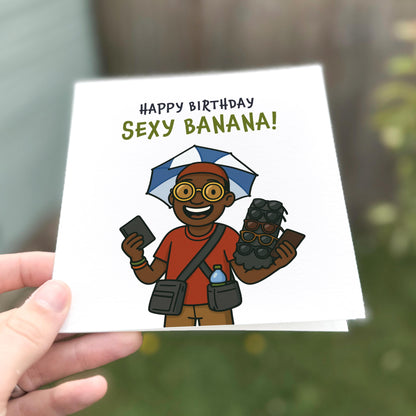 Hand holding a birthday card with a cartoon character and 'Happy Birthday Sexy Banana!' text.