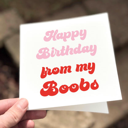 Hand holding a birthday card with 'Happy Birthday from my Boobs' text.
