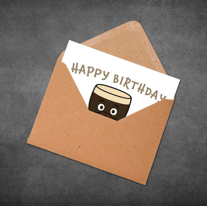 Brown envelope with a birthday card featuring a cake illustration on a dark gray background