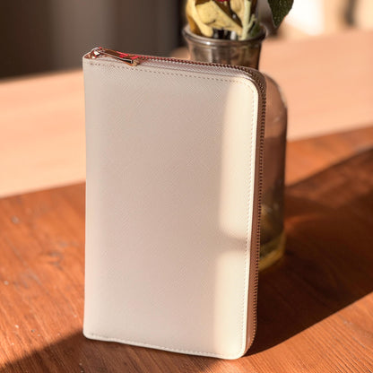 White wallet with a gold zipper on a wooden surface
