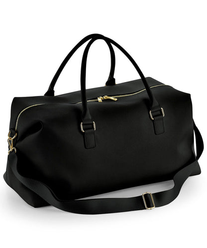 Black duffel bag with gold zippers on a white background