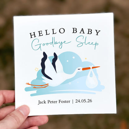 Baby shower card with stork illustration and text 'Hello Baby, Goodbye Sleep' held by a hand.