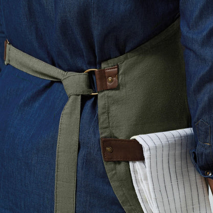 Person wearing a blue shirt with a green apron and brown belt