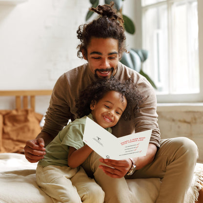 Man and child sitting together, looking at a piece of paper in a bright room.