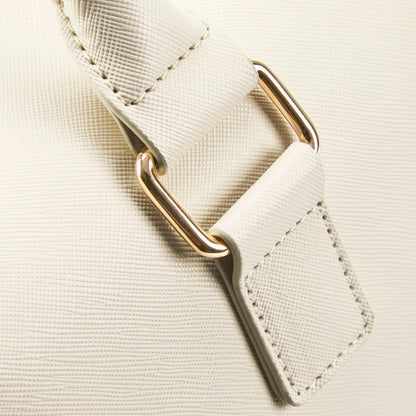 Close-up of a beige strap with a gold metal clip on a matching beige background