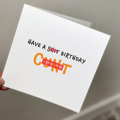 Card with offensive text held by a hand against a neutral background