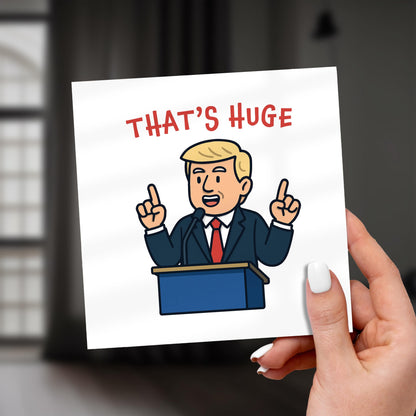 Hand holding a card with a cartoon character and 'THAT'S HUGE' text.