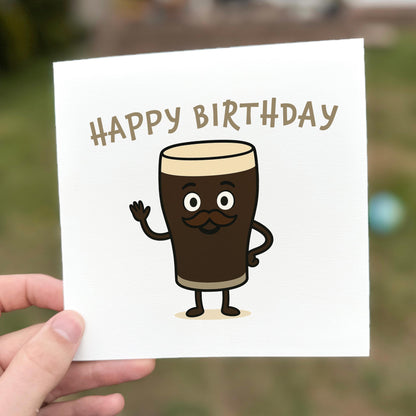 Hand holding a birthday card with a cartoon beer glass character and 'Happy Birthday' text.