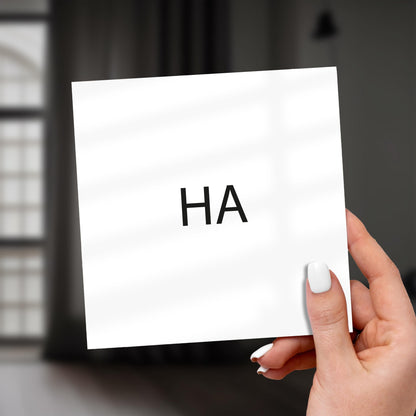 Hand holding a white card with 'HA' on it against a blurred background