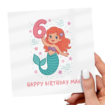 Birthday card with a mermaid holding the number 6, held by a hand.
