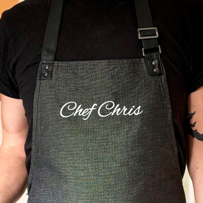 Person wearing a gray apron with 'Chef Chris' embroidered on it.