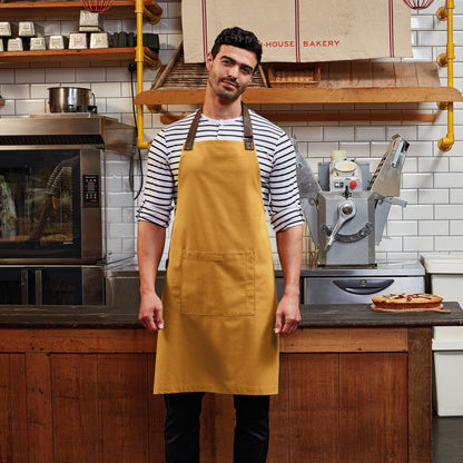 Man wearing a mustard apron in a bakery kitchen