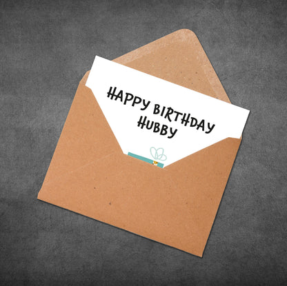 Brown envelope with a white card inside reading 'Happy Birthday Hubby' on a dark gray background