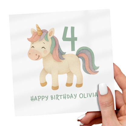 Hand holding a birthday card with a unicorn illustration and the number 4.