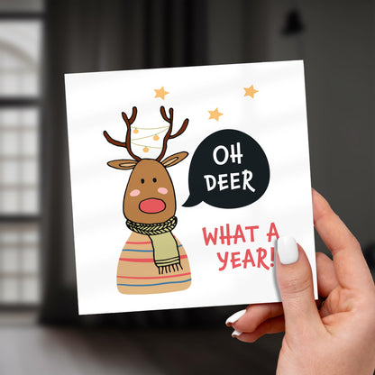 Card with a reindeer illustration and text 'Oh Deer What a Year!' held by a hand.