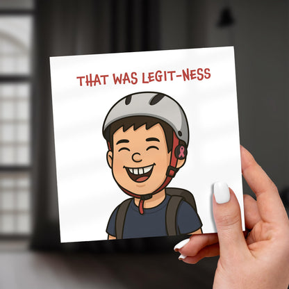 Hand holding a card with a cartoon character wearing a helmet and text 'THAT WAS LEGIT-NESS'.