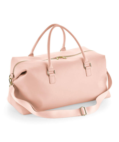 Pink duffel bag with gold zippers on a white background